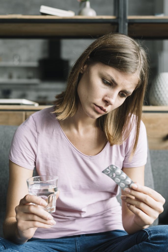 young-woman-sitting-sofa-looking-pill-blister-pack